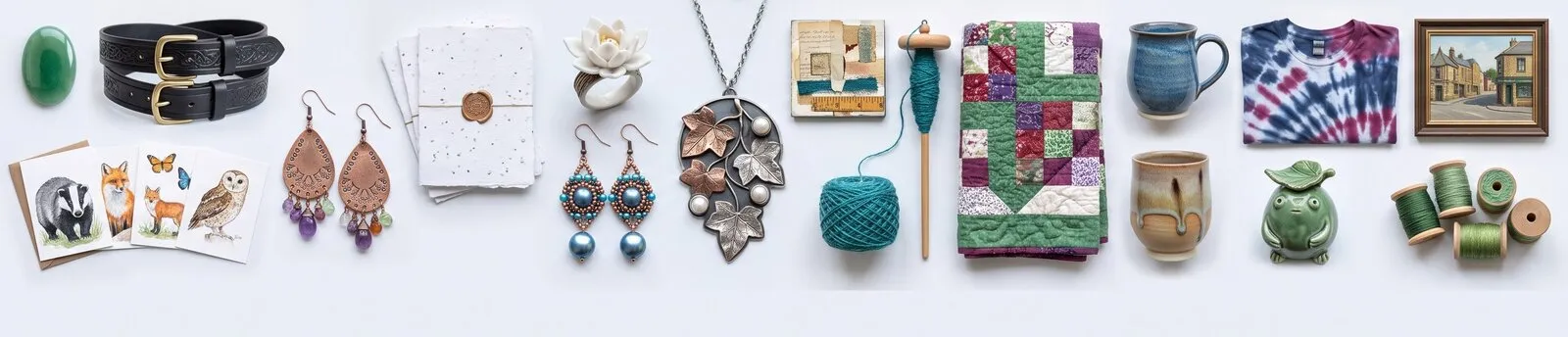 A row of handmade pieces: notecards, a tooled belt, earrings, a pendant, a collage, a spindle of yarn, a quilt, a mug, a tie-dyed shirt and a framed painting